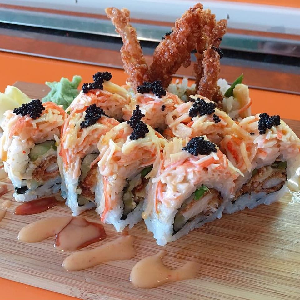 J-Dao Sushi Thai's sushi rolls with crab, avocado, fried shrimp, and black caviar on a wooden board.
