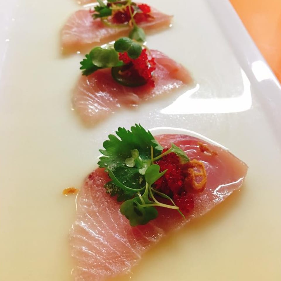 Three pieces of J-Dao Sushi Thai sashimi with red roe and green herbs on a white plate.
