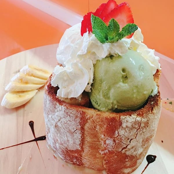 J-Dao Sushi Thai honey toast dessert with matcha ice cream, whipped cream, strawberries, and bananas.