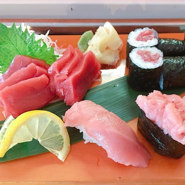 A vibrant platter of J-Dao Sushi Thai's tuna sashimi, nigiri, and maki rolls with lemon, ginger, and wasabi.
